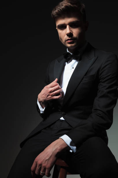 istock seductive man in black tuxedo sitting and holding collar 1057921578