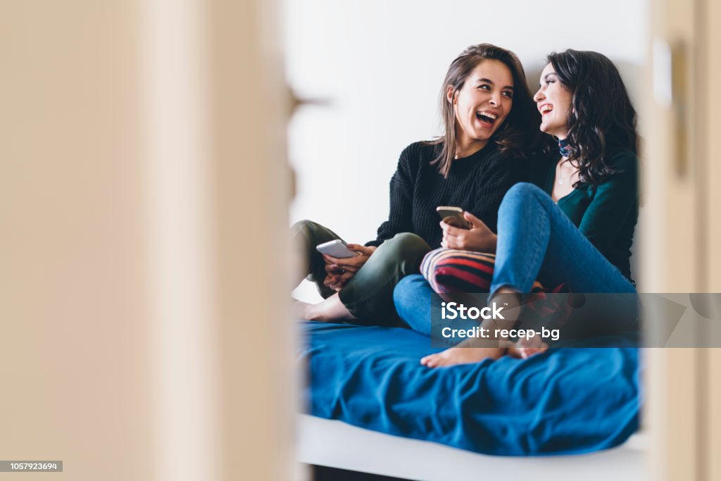 Two young women friends sharing happy time together Two young women friends are talking and laughing happily at home. Friendship Stock Photo