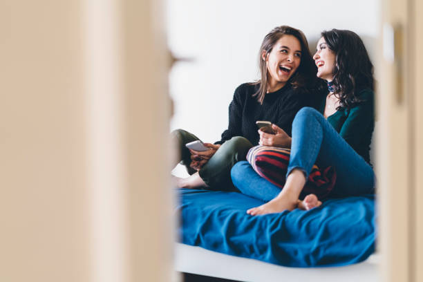 Two young women friends sharing happy time together Two young women friends are talking and laughing happily at home. friends stock pictures, royalty-free photos & images