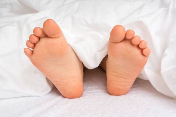 istock Little baby feet in bed under the white blanket 1057929304