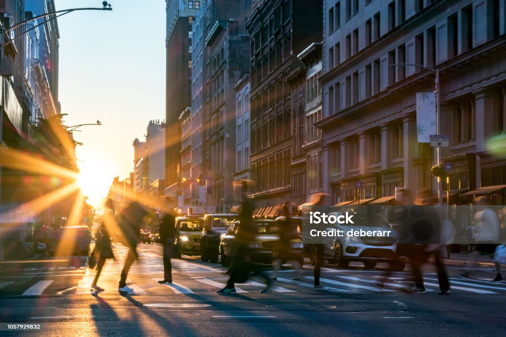 People crossing the street in Manhattan New York City Rays of sunlight shine on the busy people walking across an intersection in Midtown Manhattan in New York City NYC City Stock Photo