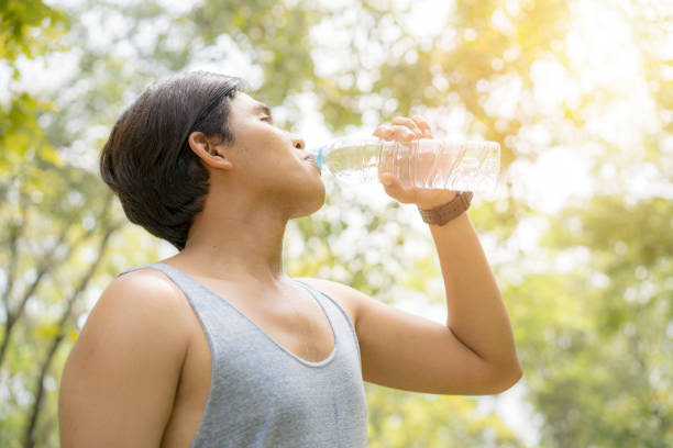 istock sporty man thirsty and drinking water after tired from jogging or exercise. 1057932682