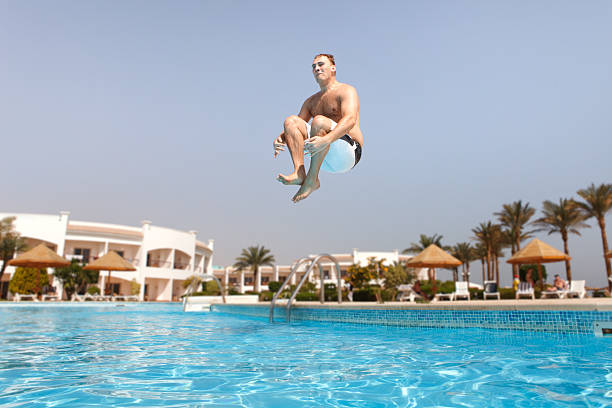 homme de sauter dans la piscine - floating on water swimming pool men water photos et images de collection