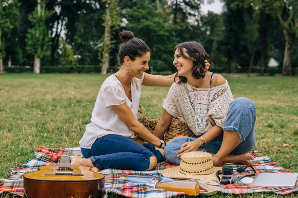 Two happy young women hugging outdoor on a blanket