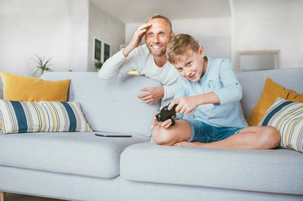 istock Father watching his son playing TV video game using the gamepad 1057936522