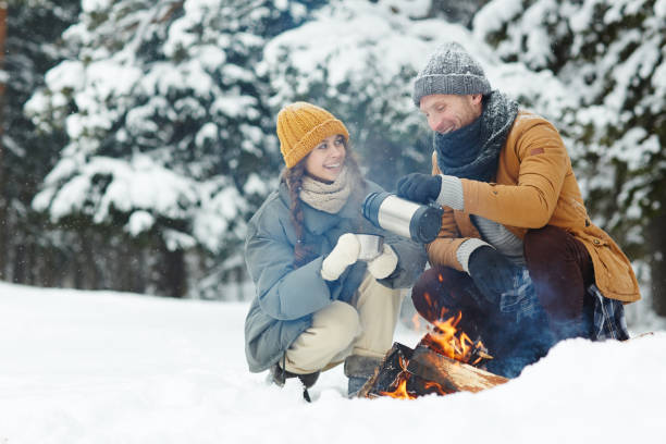 istock Happy couple drinking hot tea and sitting by fire 1057945540