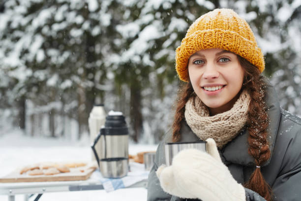 istock Smiling attractive girl drinking from thermos mug 1057945660