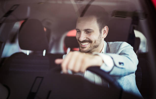 attraente giovane felice alla guida di auto e sorridente - car driving men business foto e immagini stock
