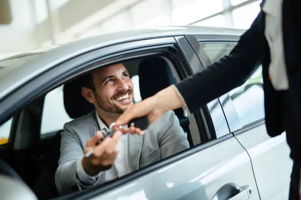 Photo of Professional salesperson during work with customer at car dealership.