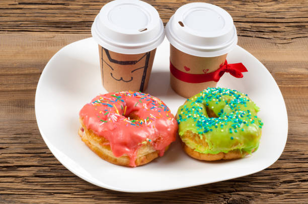 istock Multi-colored glazed donuts. On a white plate, on wooden boards. Coffee to donuts 1057946598