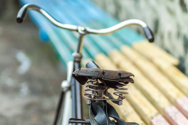 An old bicycle seat with a spring shock absorber. Vintage bicycle on the stone wall background.