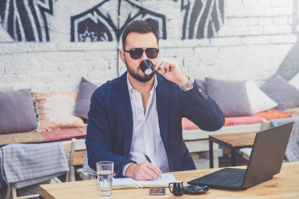 istock Handsome businessman drinking coffee in coffee shop and making notes. 1057953328
