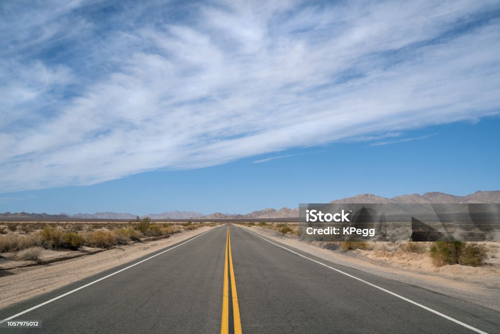 Desert Highway in California Empty Desert Highway running from California to Arizona. Sunny day blue sky with clouds Highway Stock Photo