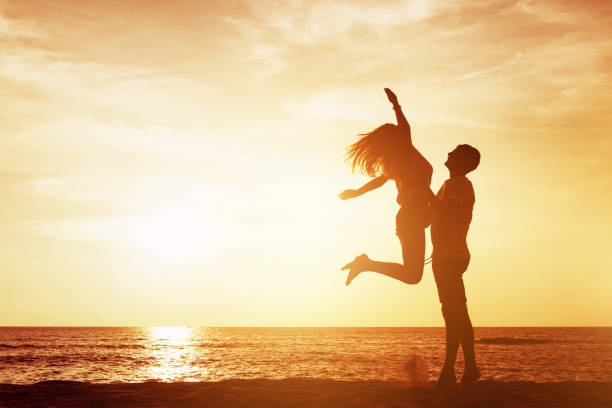istock Happy couple silhouette against sea beach sunset 1057979208