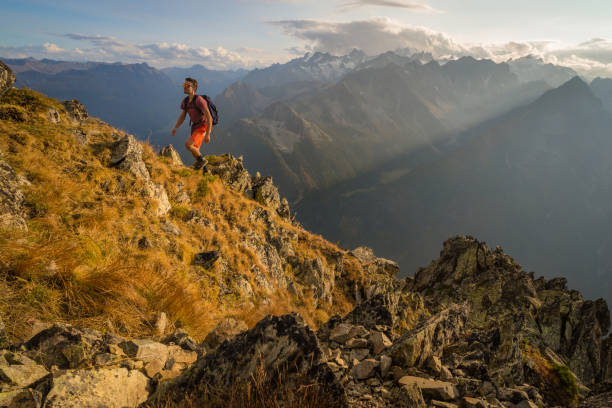 A man walking up a mountain in Switzerland with a beautiful sunset over Mont Blanc and the Chamonix range of mountains in the background.