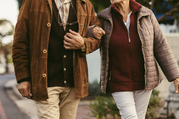 senior couple walking holding hands - couple walking old middle imagens e fotografias de stock