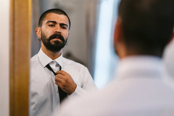 istock Young businessman taking off his clothes in front of mirror 1057994008