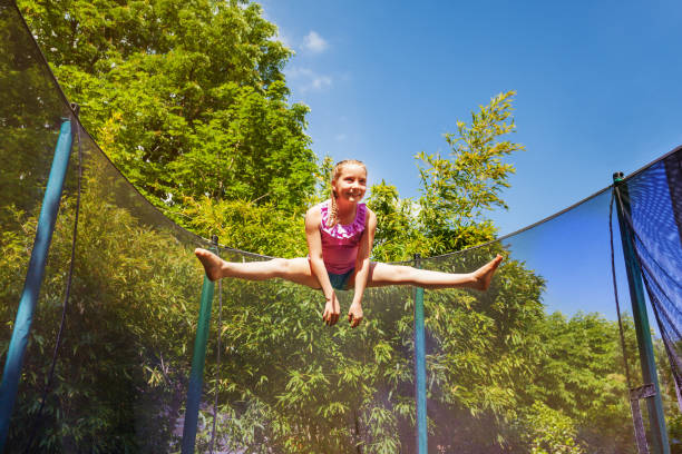 istock Happy girl performing split jump on the trampoline 1057996044