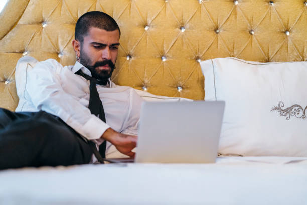 istock Young businessman relaxing on bed and working on laptop 1057996316