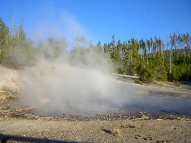 a geyser in the rocky montains with lot of steam