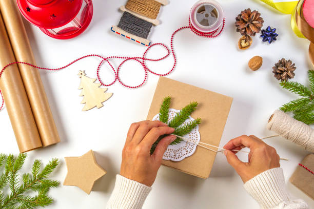 istock Christmas gift wrapping. Woman's hands packing Christmas presents on white table 1058000586