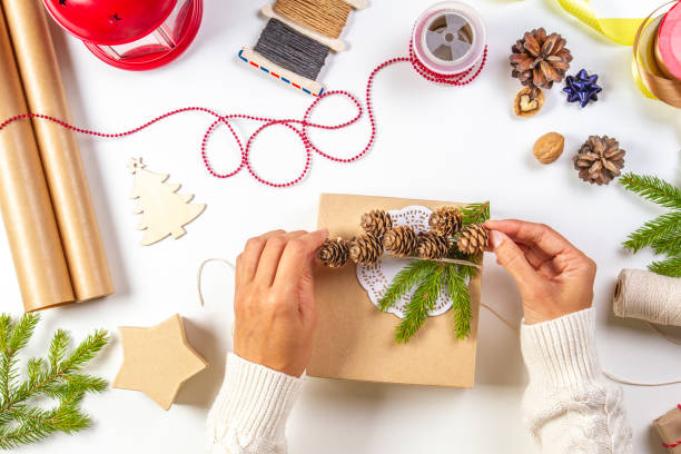 istock Christmas gift wrapping. Woman's hands packing Christmas presents on white table 1058000814