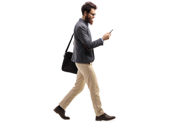 istock Man walking and looking into a mobile phone 1058004766