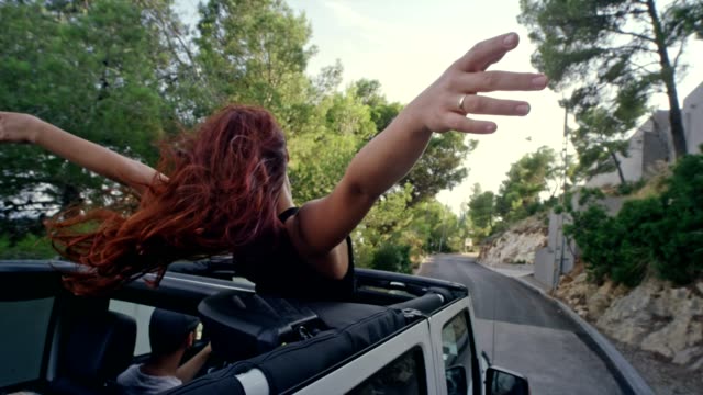 Redhead girl having fun in a SUV with sun roof