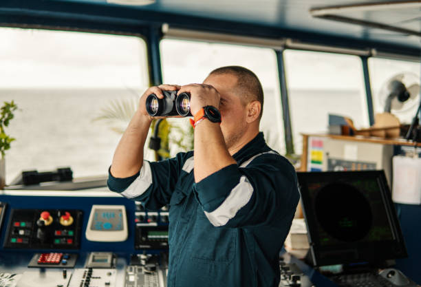 istock Navigational officer lookout on navigation watch looking through binoculars 1058010718