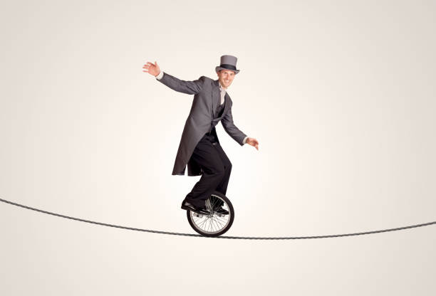hombre de negocios extrema montando monociclo sobre una cuerda - acróbata circo fotografías e imágenes de stock