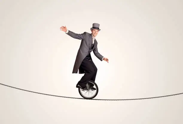 Extreme business man riding unicycle on a rope concept on background