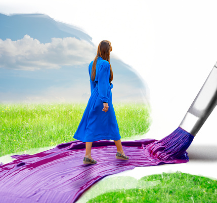 Young woman walking on a painted path and the huge brush paints that path while she is walking forward. Believe in yourself concept.