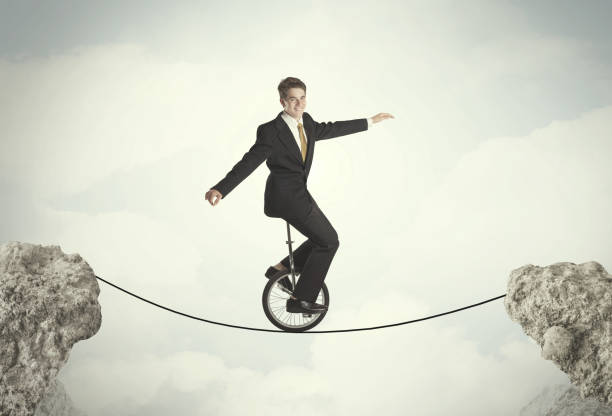 istock Brave business man riding an mono cycle between cliffs 1058017772