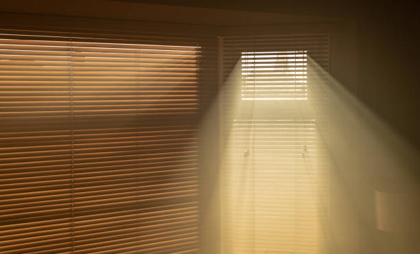 istock Sun streaming through window blinds into a smoky room 1058023196