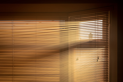 Sun streaming through blinds into a smoky room