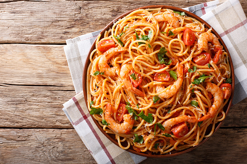 Spicy spaghetti with shrimps in tomato sauce close-up on a plate. horizontal top view from above