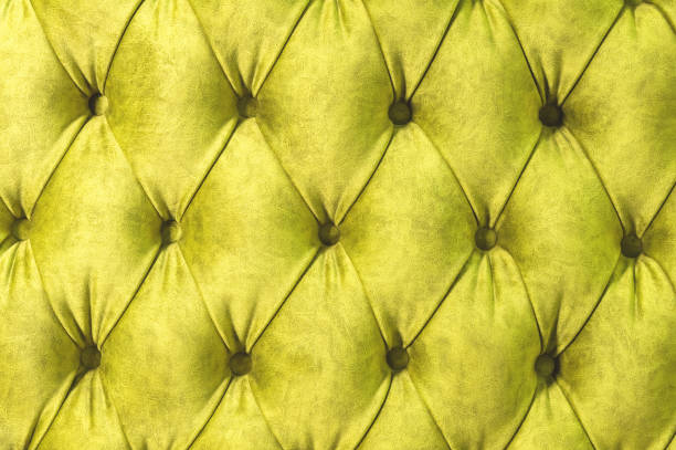 istock Velor surface of sofa close-up. Training equipment-velor mats tightened with buttons. Yellow chesterfield style quilted upholstery background close up 1058029494