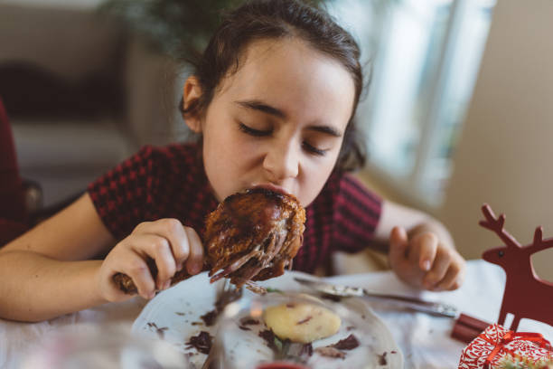 cute little girl eating rosted duck leg at Christmas table