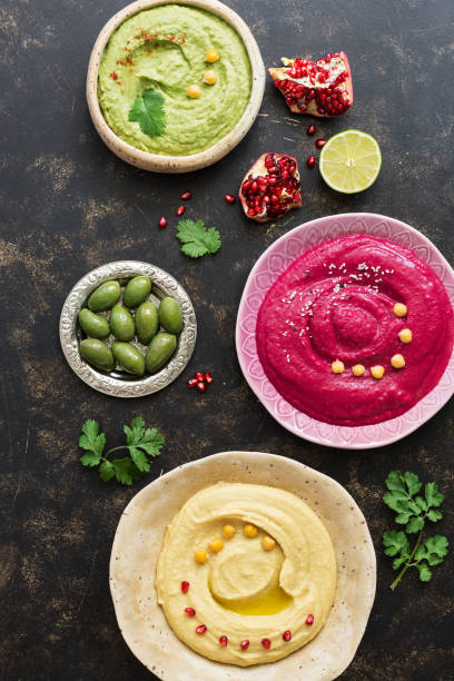 istock A variety of colored hummus, classic hummus, beet hummus, hummus with avocado on a dark rustic background. Top view, flat lay. Clean eating, dieting, vegetarian party food 1058032428