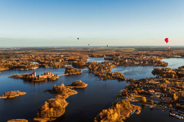 Flying over castle lake hot air balloon Flying over Trakai castle surrounded with lake with hot air balloons in the sky lithuania stock pictures, royalty-free photos & images