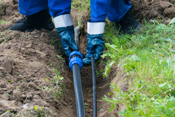 istock hands hold a black pipe over a dug hole in the ground 1058043840