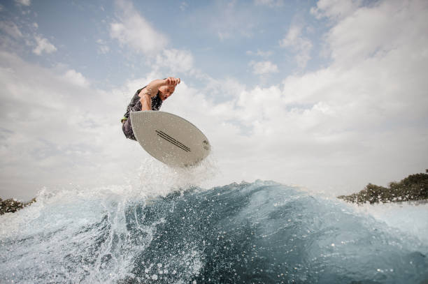 uomo attivo che salta sul wakeboard sull'onda - wakeboarding surfing men vacations foto e immagini stock