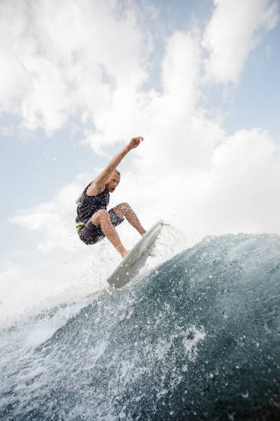 istock Young active man jumping up on the white wakeboard on the high wave 1058044694