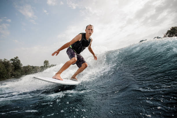 istock Active man riding on the white wakeboard on the high wave 1058044958