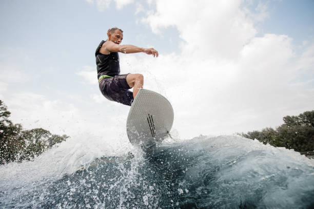 istock Active man jumping up on the white wakeboard on the high wave 1058045390