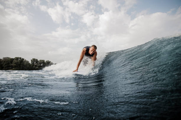 istock Young active man standing on the one knee on the white wakeboard 1058046028