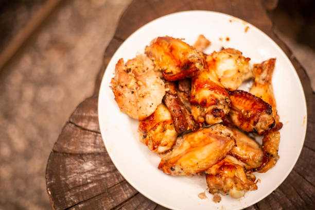 istock Spicy chicken wings and legs grilling with hot flames. 1058048060