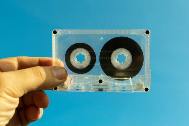 audiocassetta trasparente in mano su sfondo blu - human finger audio foto e immagini stock