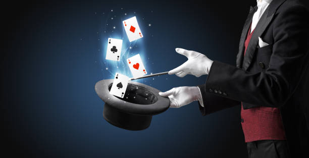 istock Magician making trick with wand and playing cards 1058051450