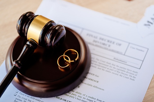 Divorce decree in and two broken wedding rings on judge gavel. Divorce and separation concept